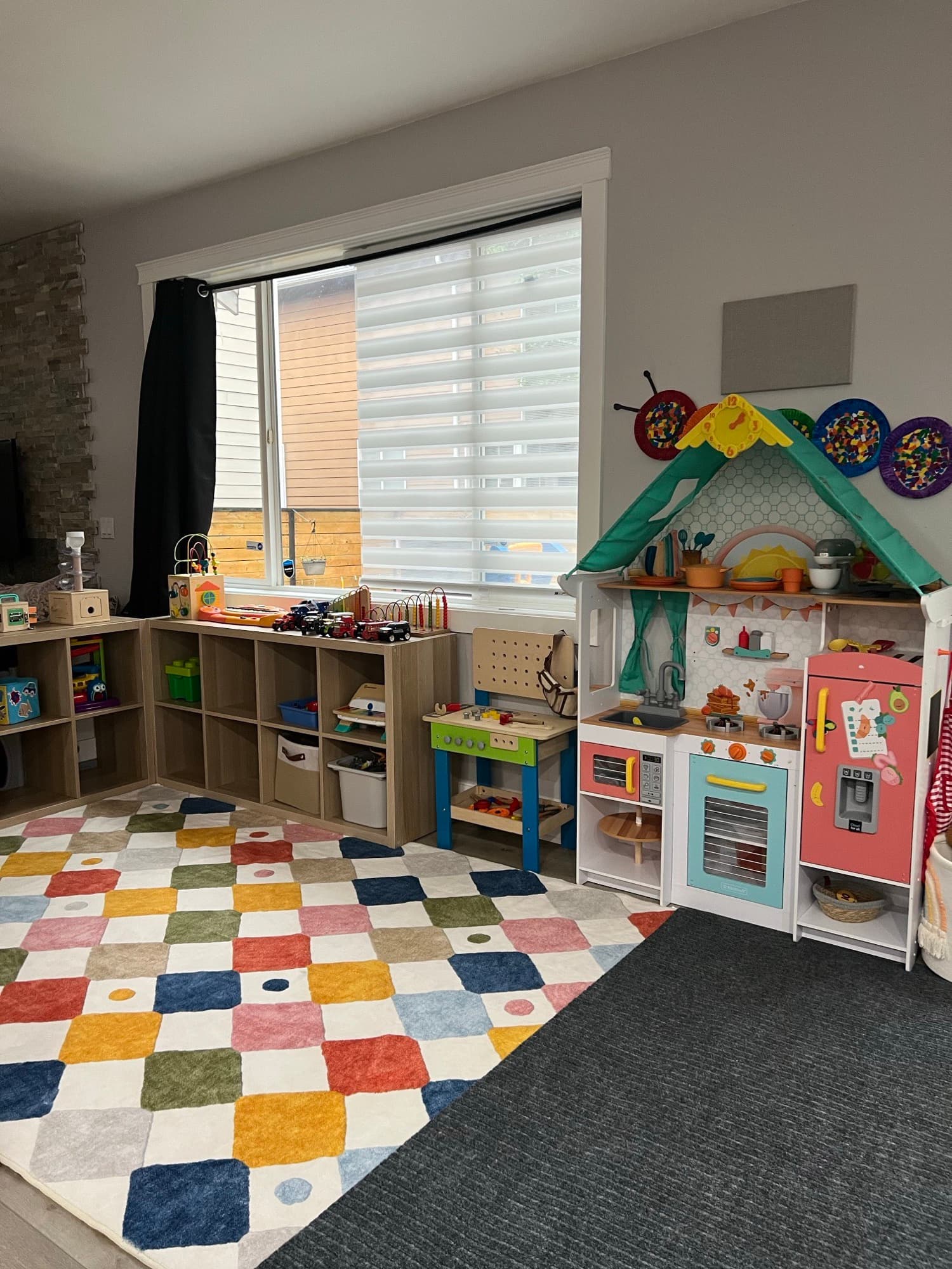 The home classroom — bookshelves, play kitchen, and patchwork rug