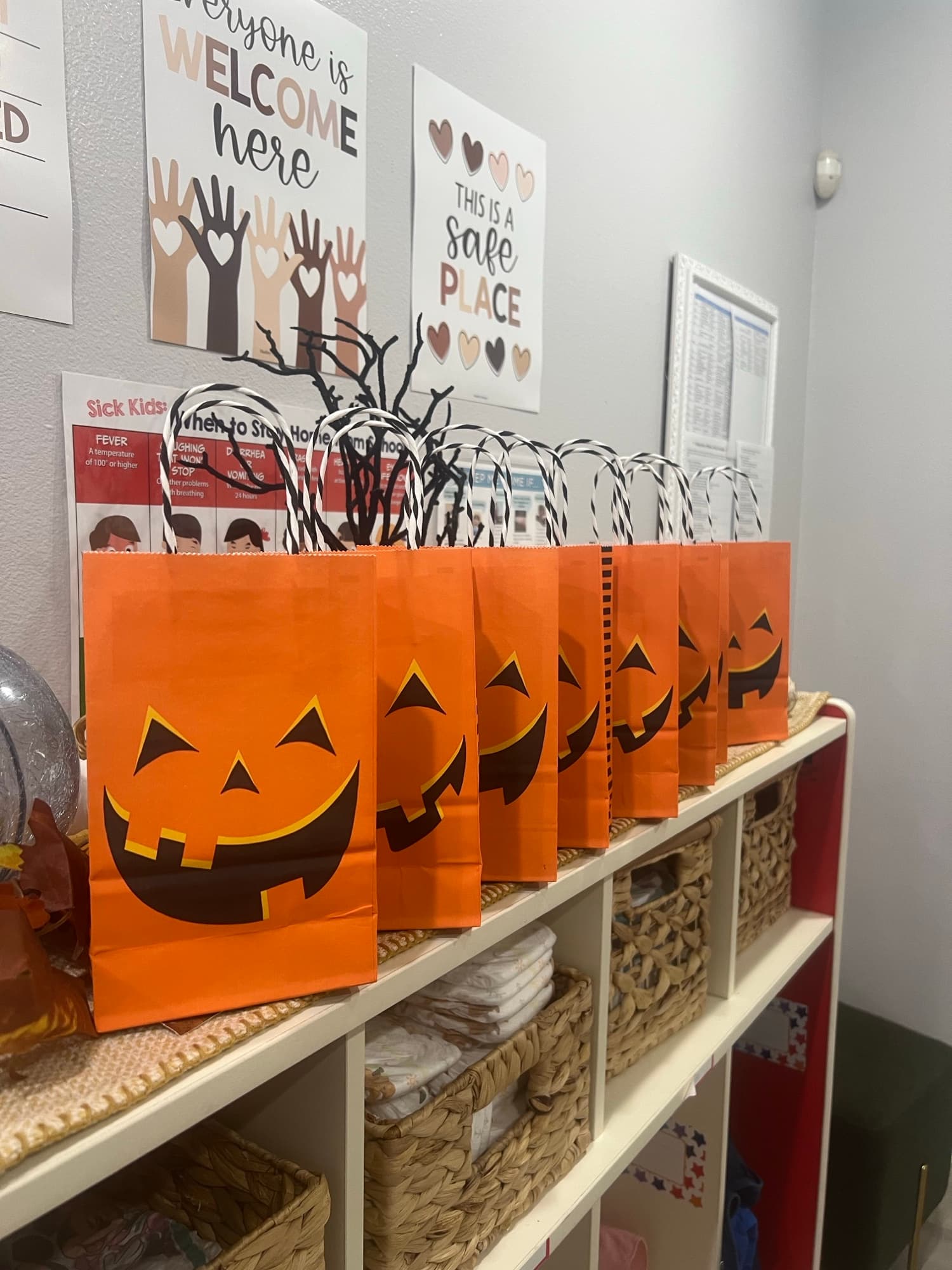 Halloween jack-o-lantern bags alongside Welcome Here and Safe Place signs