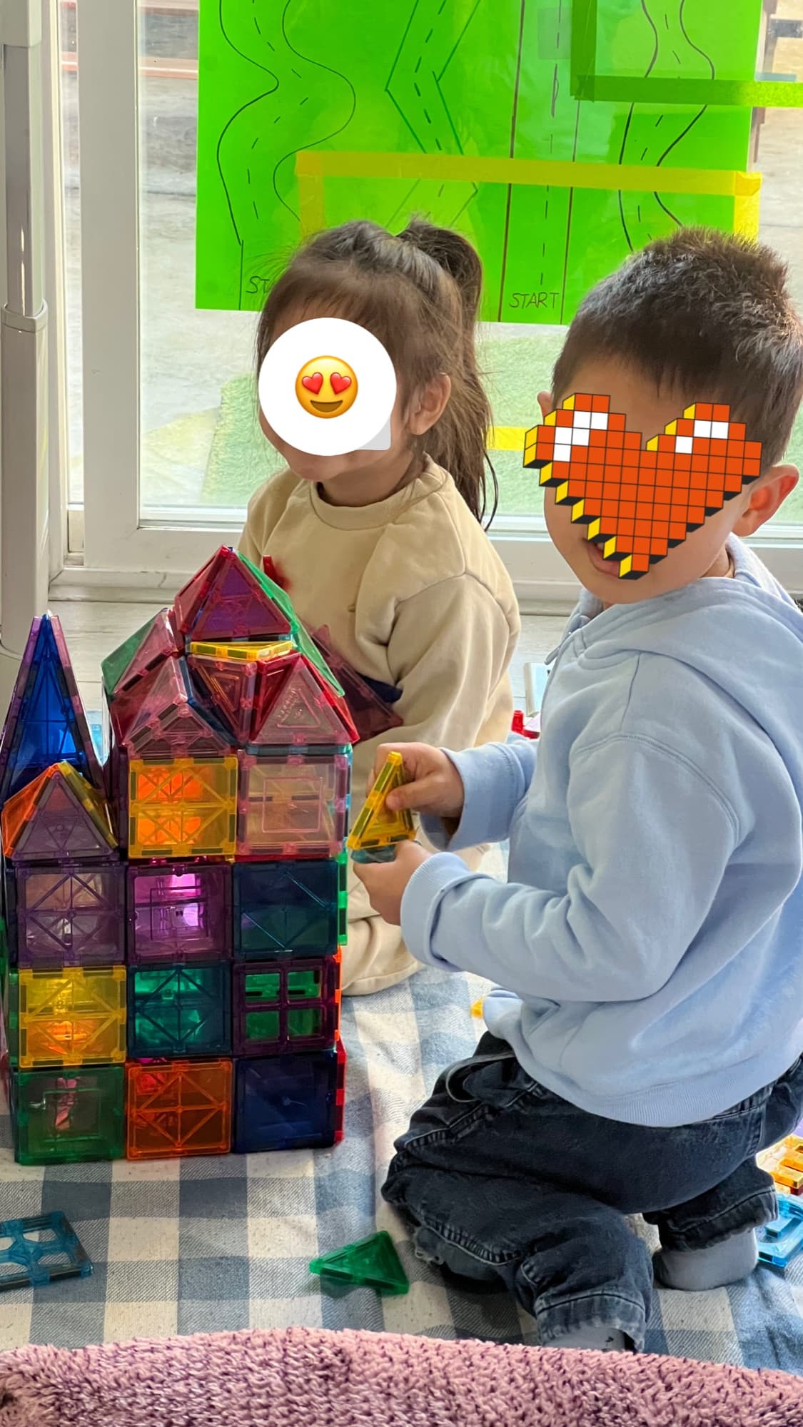 Children building a structure together with magnetic tiles