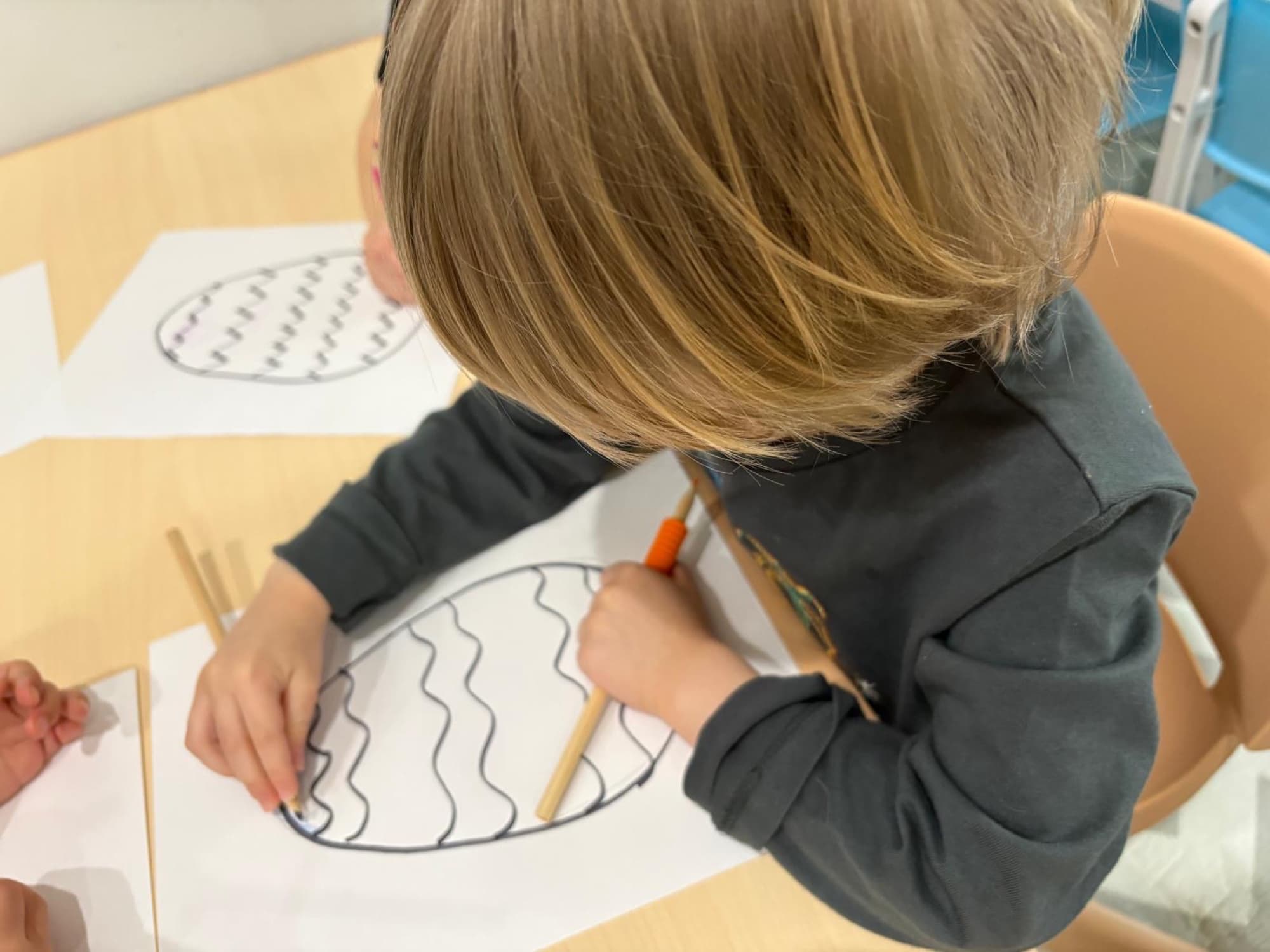 Overhead view of a child carefully coloring an Easter egg pattern